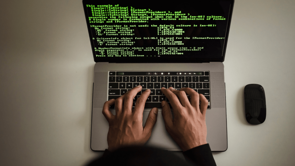 a person typing on a laptop computer with code on the screen