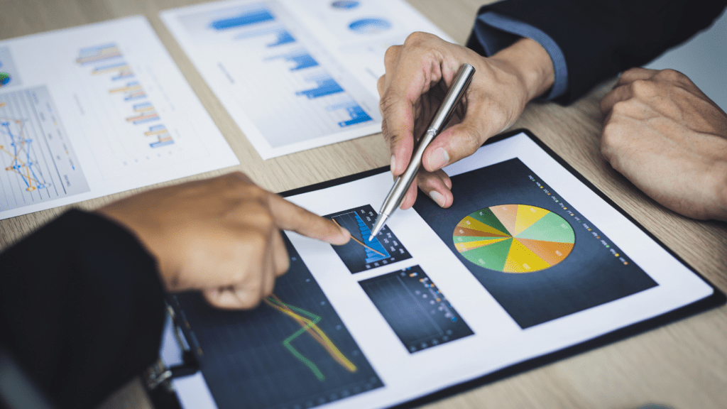 Two business people are looking at graphs on a clipboard