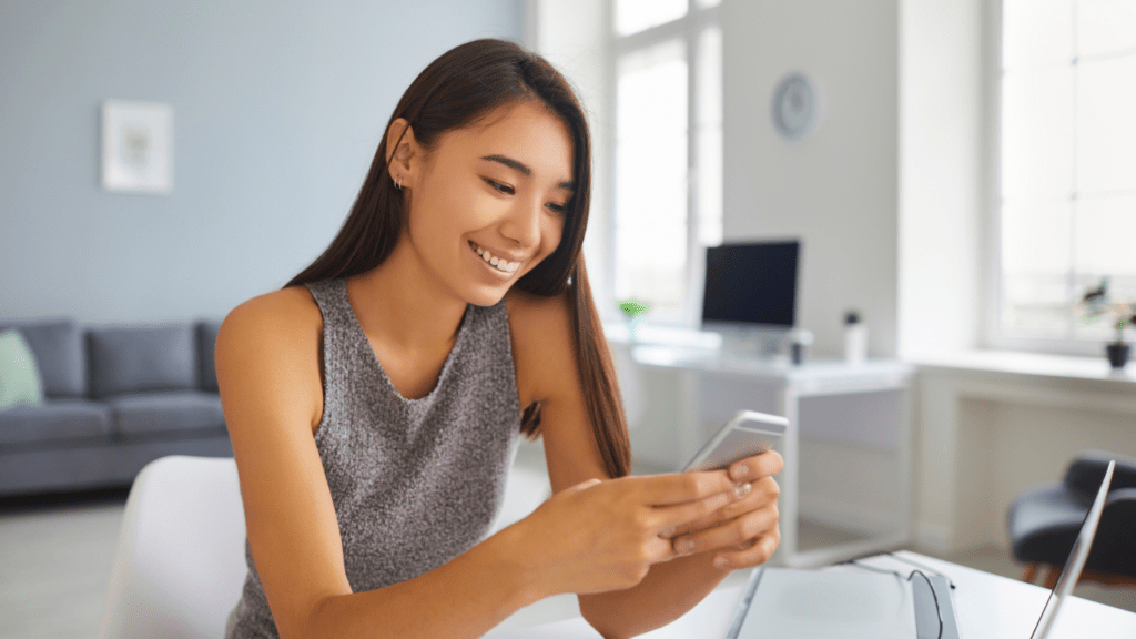 a person smiling while looking at their phone