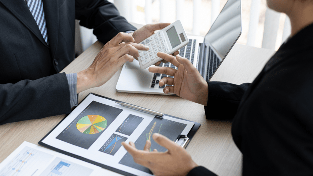 Two business people are looking at graphs on a clipboard