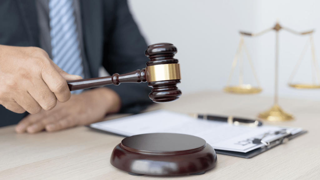 a person in a suit is holding a gavel in front of a desk